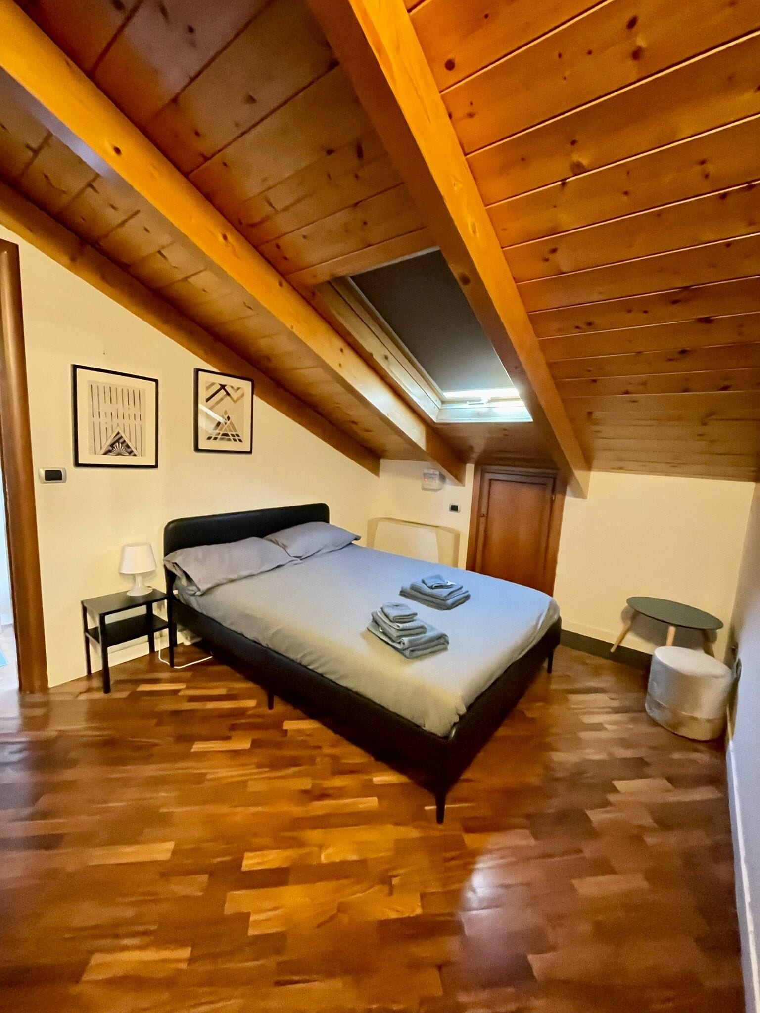 Un dormitorio con techo de madera, una cama, una mesita de noche y una pequeña mesa.