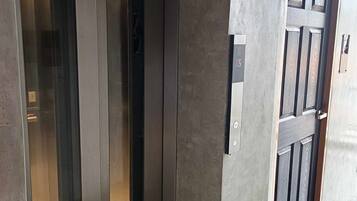Un ascensor moderno con panel de control y puerta de diseño texturizado.