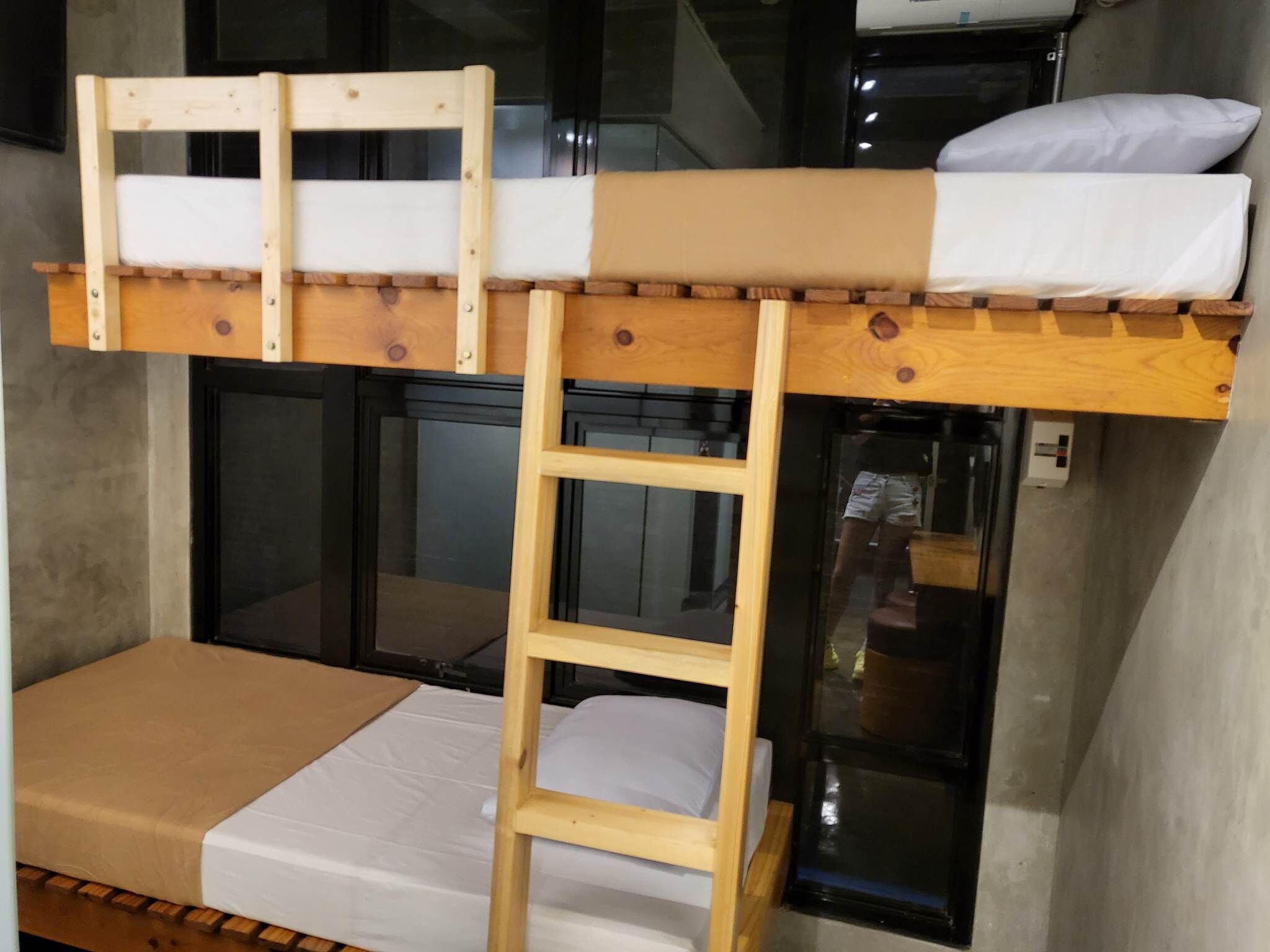 Una cama individual superpuesta con escalera de madera, un colchón y una almohada.