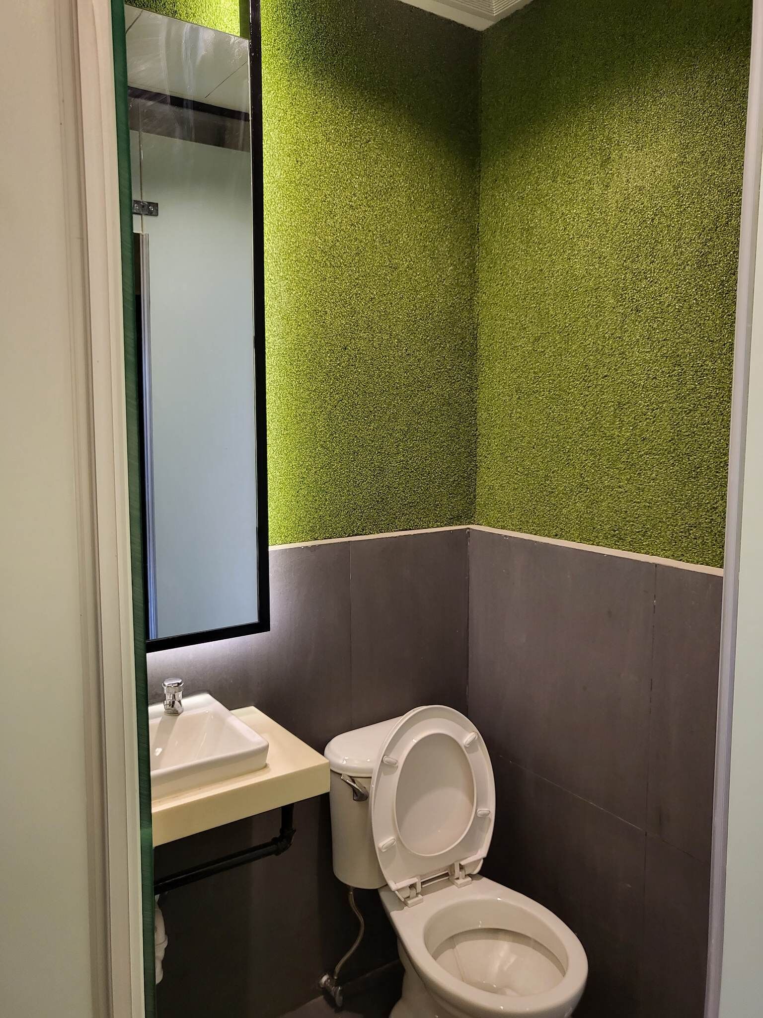 A bathroom with a toilet, sink, and mirror.