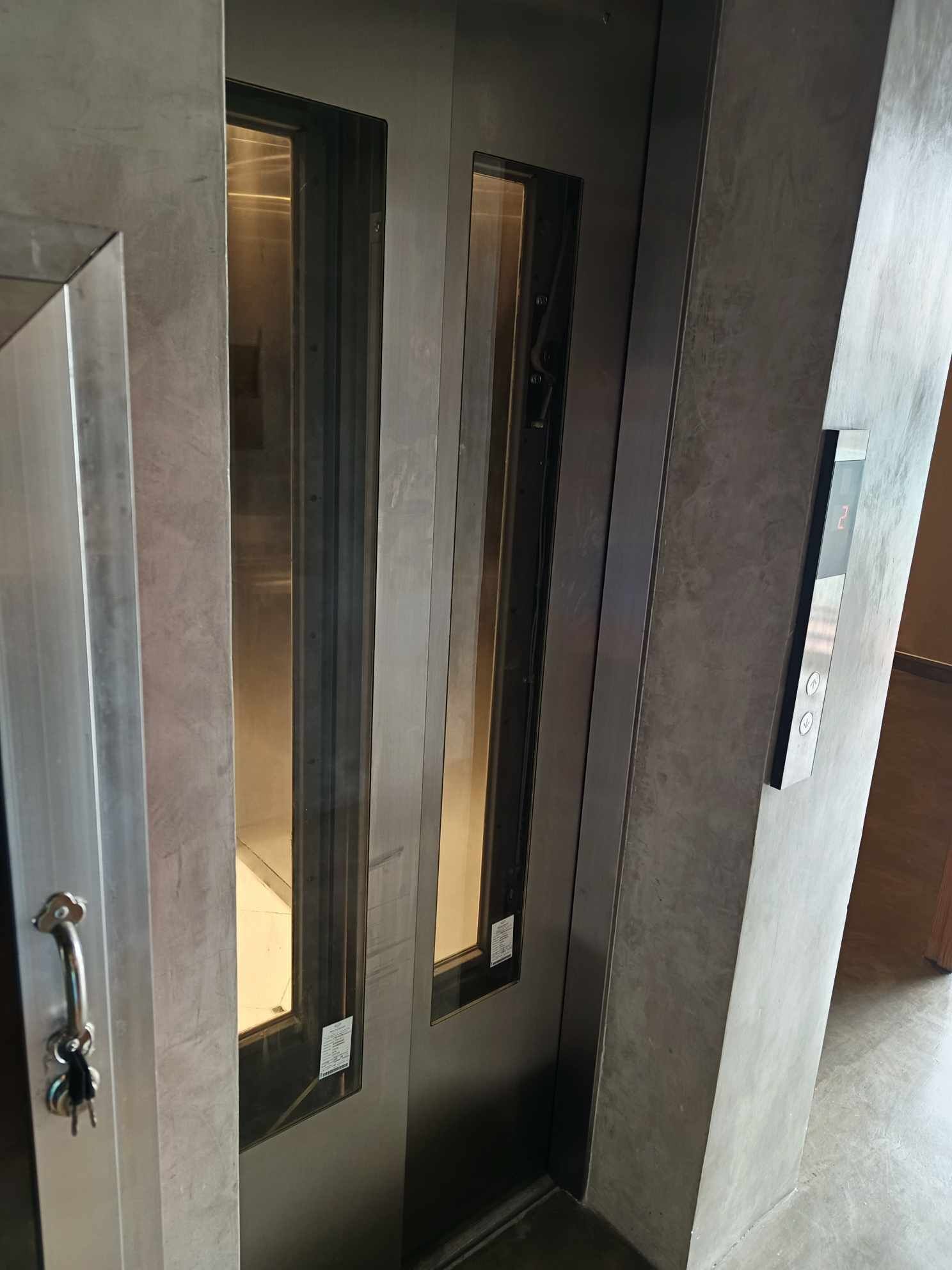 A modern elevator with metallic walls and glass panels.