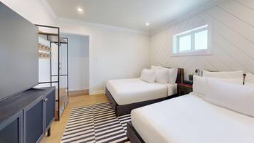 Quarto com duas camas, um guarda-roupa, uma escrivaninha e uma janela.