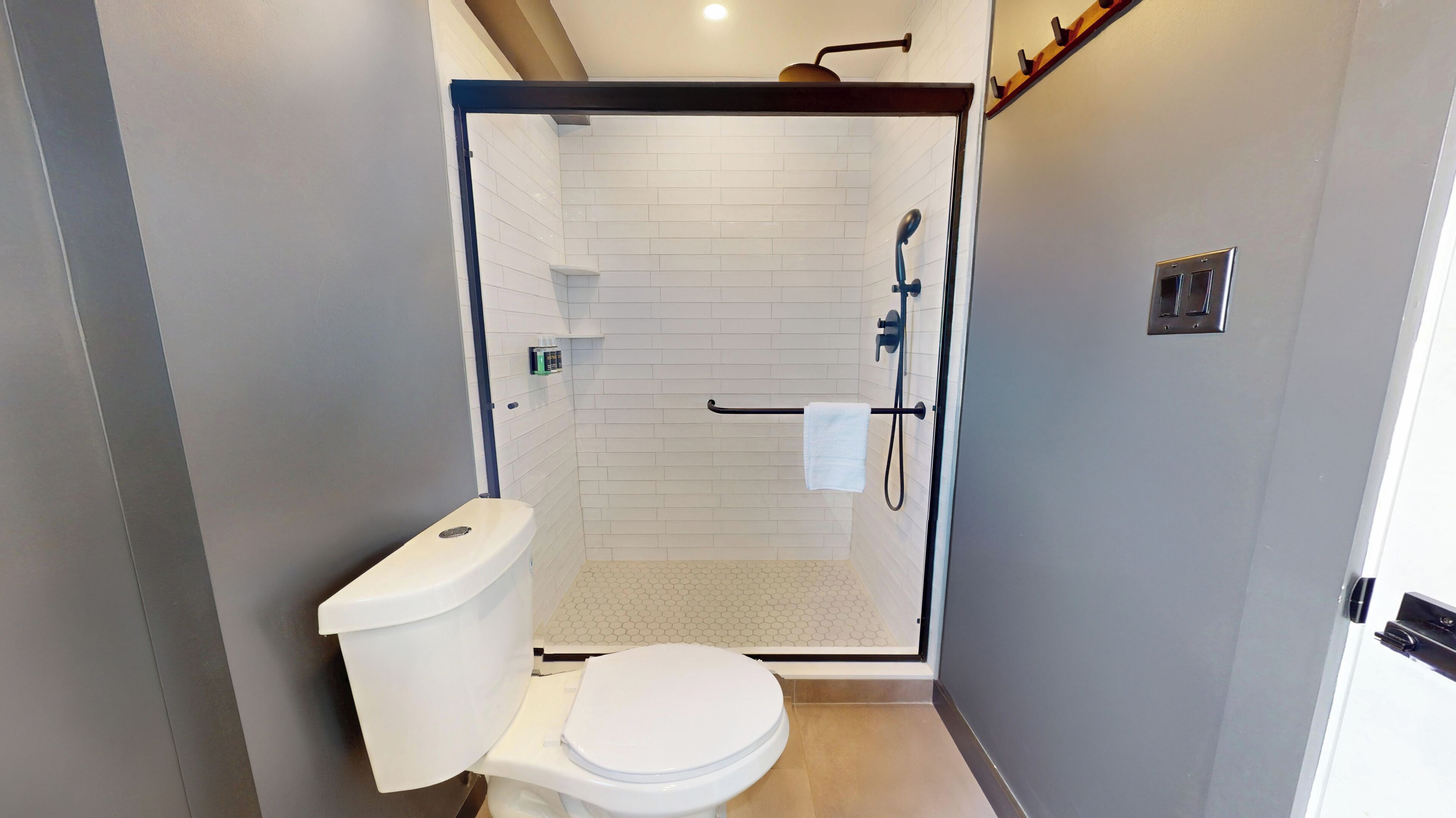 A compact bathroom with a toilet, shower, and a towel rack.
