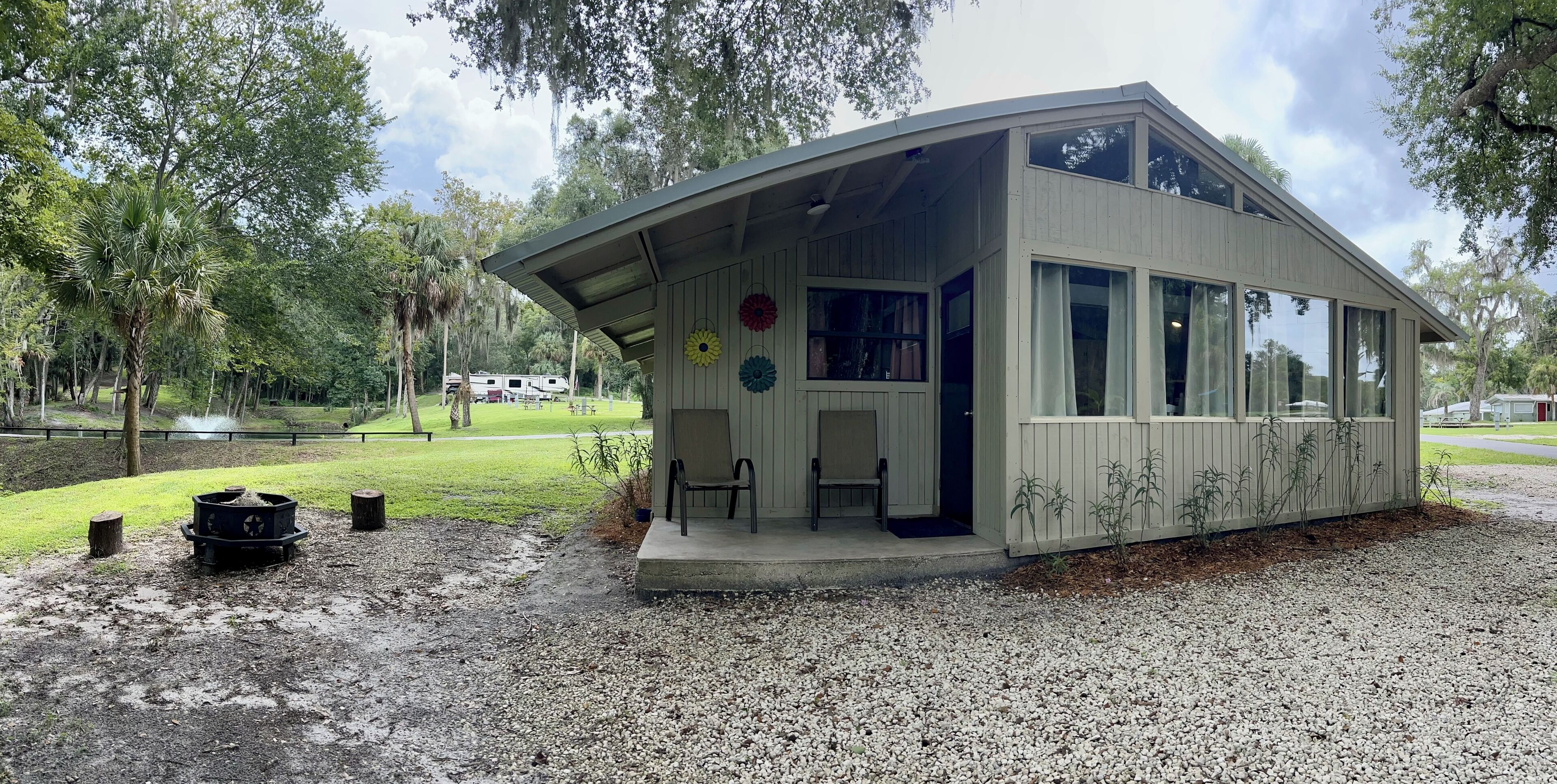 A small, single-story building with a covered porch, large windows, and a gravel driveway.
