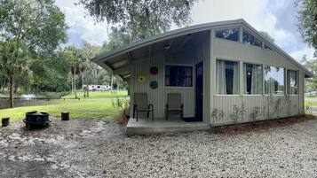 A small, single-story building with a covered porch, large windows, and a gravel driveway.