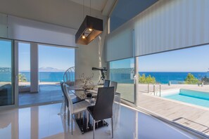 Ein modernes Interieur mit Essbereich, Pool und Meerblick.