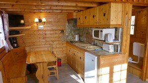 Una cocina compacta con armarios de madera, un microondas, un fregadero y un refrigerador pequeño.