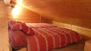 Un dormitorio abuhardinado de madera con una cama individual, paredes de madera y techo inclinado.