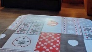 Una habitación acogedora con paredes de madera, un sofá con cojines estampados, una ventana con cortinas y dos lámparas fijadas a la pared.
