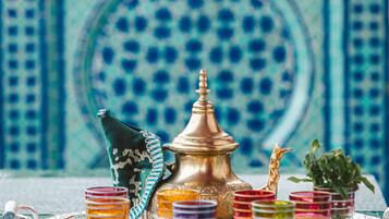 Un plateau avec une théière en laiton, des verres colorés et un tissu décoratif.