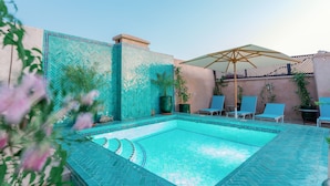 A swimming pool with tiled walls and a sun umbrella. There are lounge chairs and potted plants around the pool. - Riad El Hara (Marrakech)