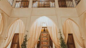 A spacious atrium with a high ceiling, a central staircase, and a skylight. - Riad El Hara (Marrakech)
