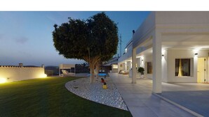 A modern building with a covered outdoor area, a tree, and a well-maintained lawn.