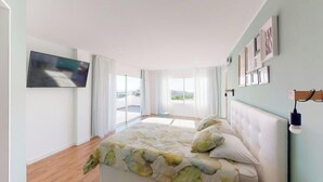 A bedroom with a bed, a TV, and a view of the outdoors.
