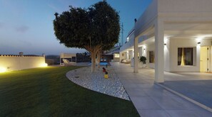 A modern building with a covered outdoor area, a tree, and a well-maintained lawn.