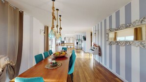 A dining area with a wooden table, blue chairs, and a fruit bowl.