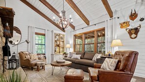 A rustic interior with a leather sofa, wooden beams, and a chandelier.