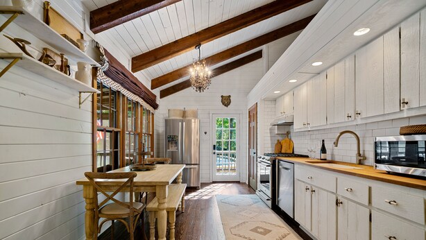 A kitchen with wooden cabinets, a dining table, and a chandelier.