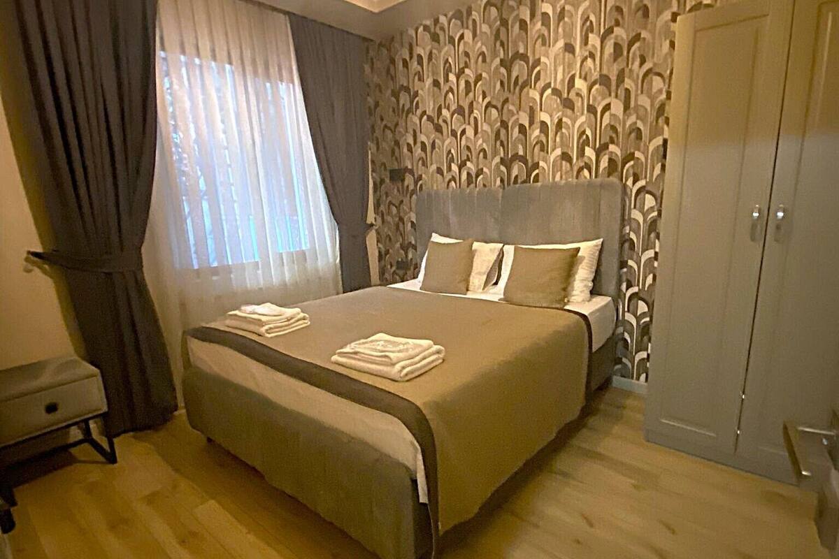 A bedroom with a large bed, a wardrobe, and a desk.