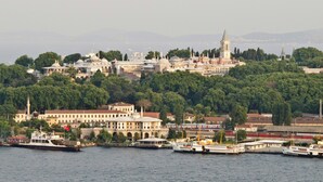 Un paysage urbain côtier avec une mosquée imposante, un terminal de traversier et une végétation luxuriante.