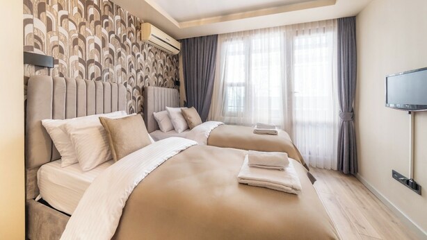 Une chambre d’hôtel avec deux lits, un téléviseur à écran plat et une grande fenêtre avec des rideaux.