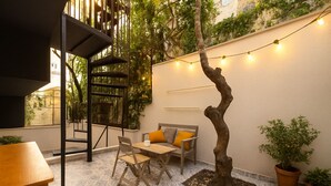 Un espace extérieur accueillant, aménagé avec une table et des chaises en bois, un petit arbre et un escalier.
