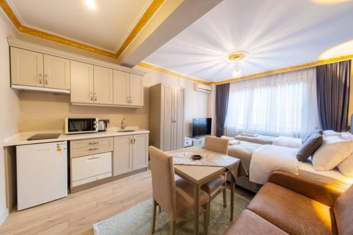 A compact hotel room with a kitchenette, a dining area, and a bed.