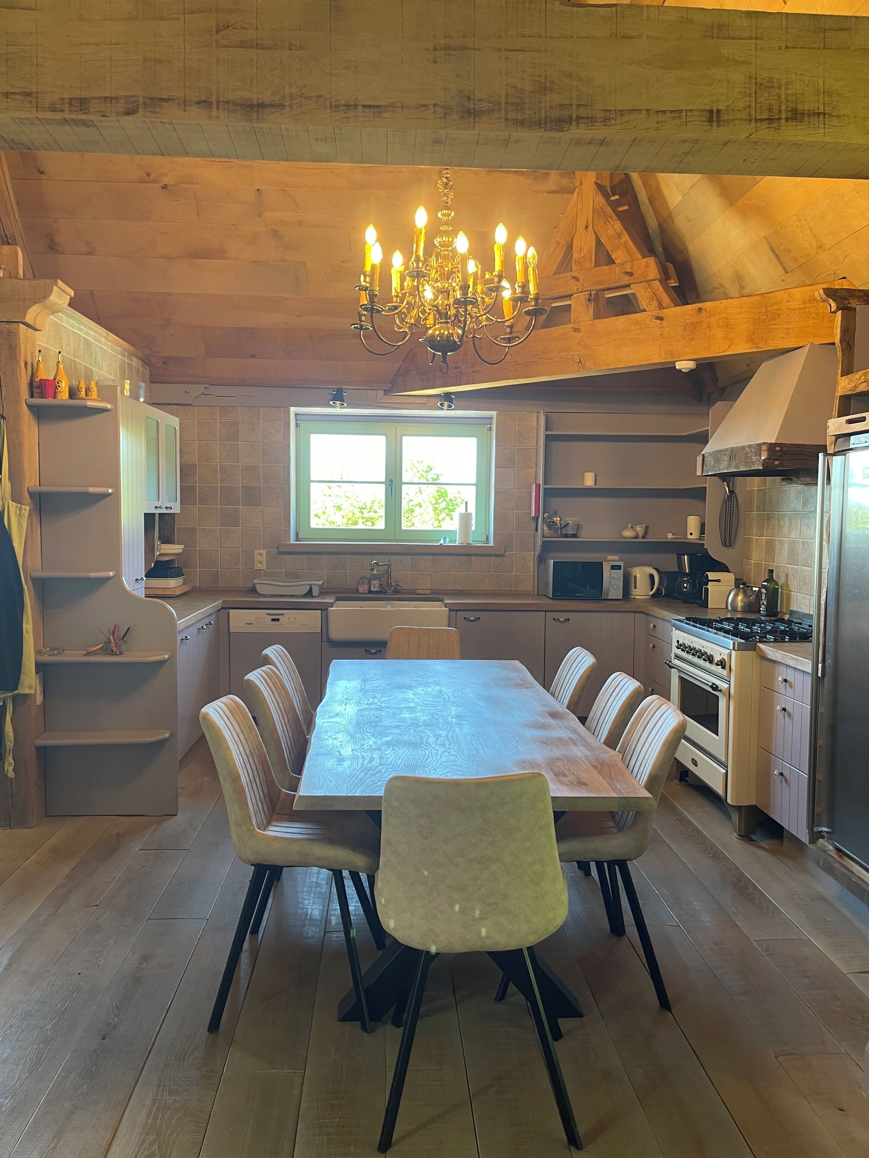 Une cuisine équipée d’une table à manger, de chaises, d’un lustre et de meubles de rangement en bois.