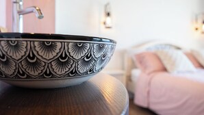 Un tazón con estampado en blanco y negro sobre una mesa, con un fondo borroso que muestra una cama y una lámpara fijada a la pared.