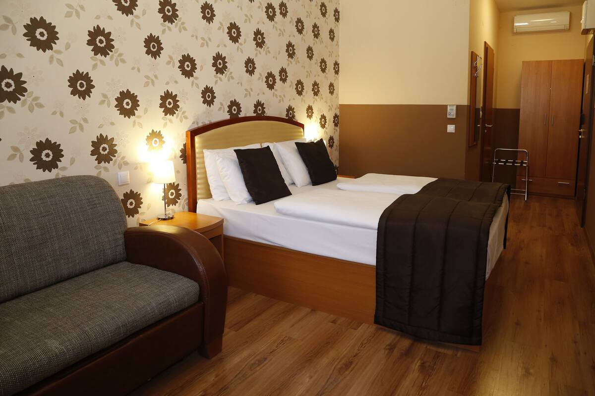 Ein Hotelzimmer mit einem Bett, einem Sessel, einem Nachttisch und einem Kleiderschrank.