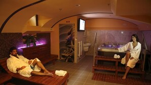 A spa room with two wooden benches, a massage table, and a television screen. - Six Inn Hotel (Budapest)