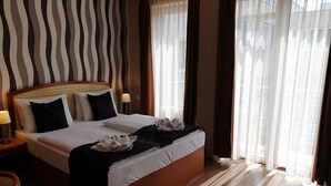 A hotel room with a large bed, wooden headboard, and a striped wall. - Six Inn Hotel (Budapest)