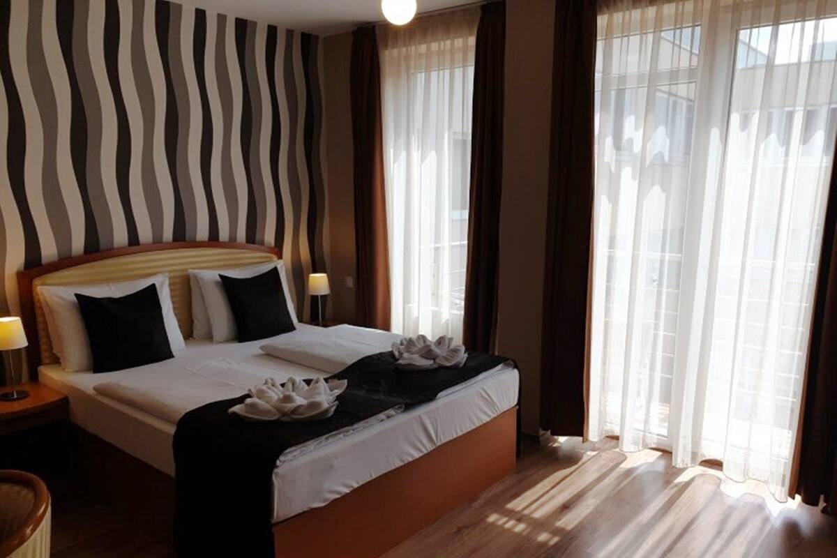 Ein Hotelzimmer mit einem großen Bett, einem hölzernen Kopfteil und einer gestreiften Wand.