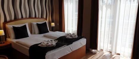 A hotel room with a large bed, wooden headboard, and a striped wall.
