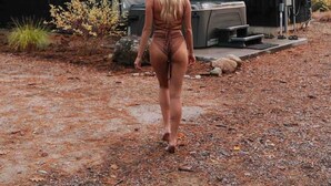 A woman walking towards a modern, dark-colored cabin with a sloped roof and a small deck area. - *NEW* Luxury A-Frame by Sunday River w/ hot tub (Bethel)