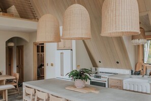A kitchen with a central island, pendant lights, and a potted plant. - *NEW* Luxury A-Frame by Sunday River w/ hot tub (Bethel)