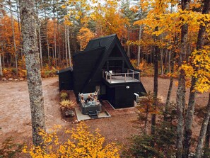 Une cabane avec une terrasse et un jacuzzi, située dans une forêt.
