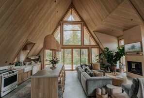 Un loft spacieux avec de hauts plafonds, un coin repas, un salon doté d’un canapé et d’une cheminée, et de grandes fenêtres offrant une vue sur l’extérieur.