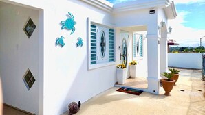 Un edificio blanco con esculturas decorativas de tortugas, un acceso cubierto y plantas en macetas.