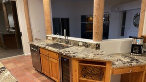 A kitchen with a granite countertop, wooden cabinets, a dishwasher, and a coffee maker.