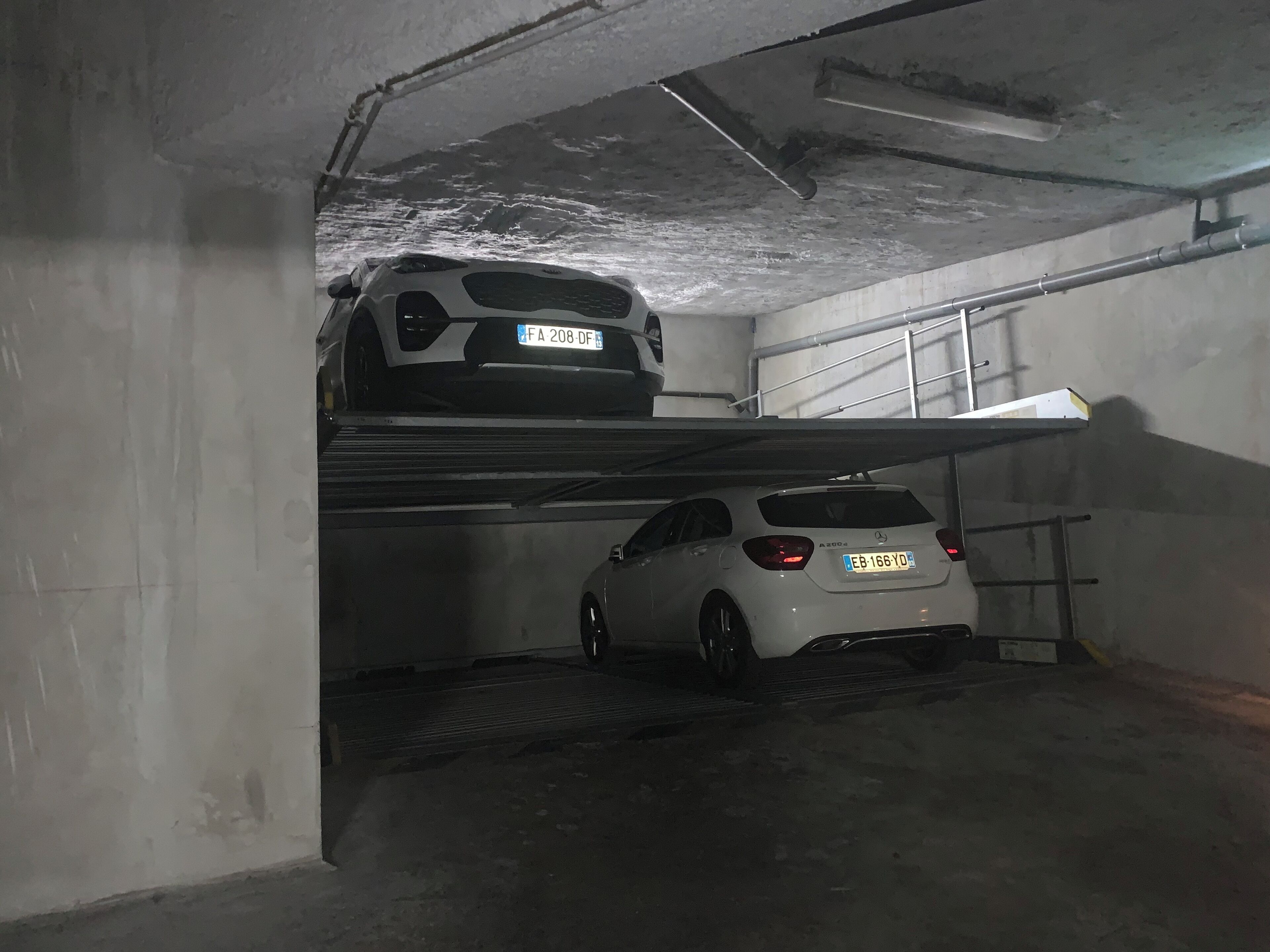 Een parkeergarage met twee auto's op verschillende niveaus.