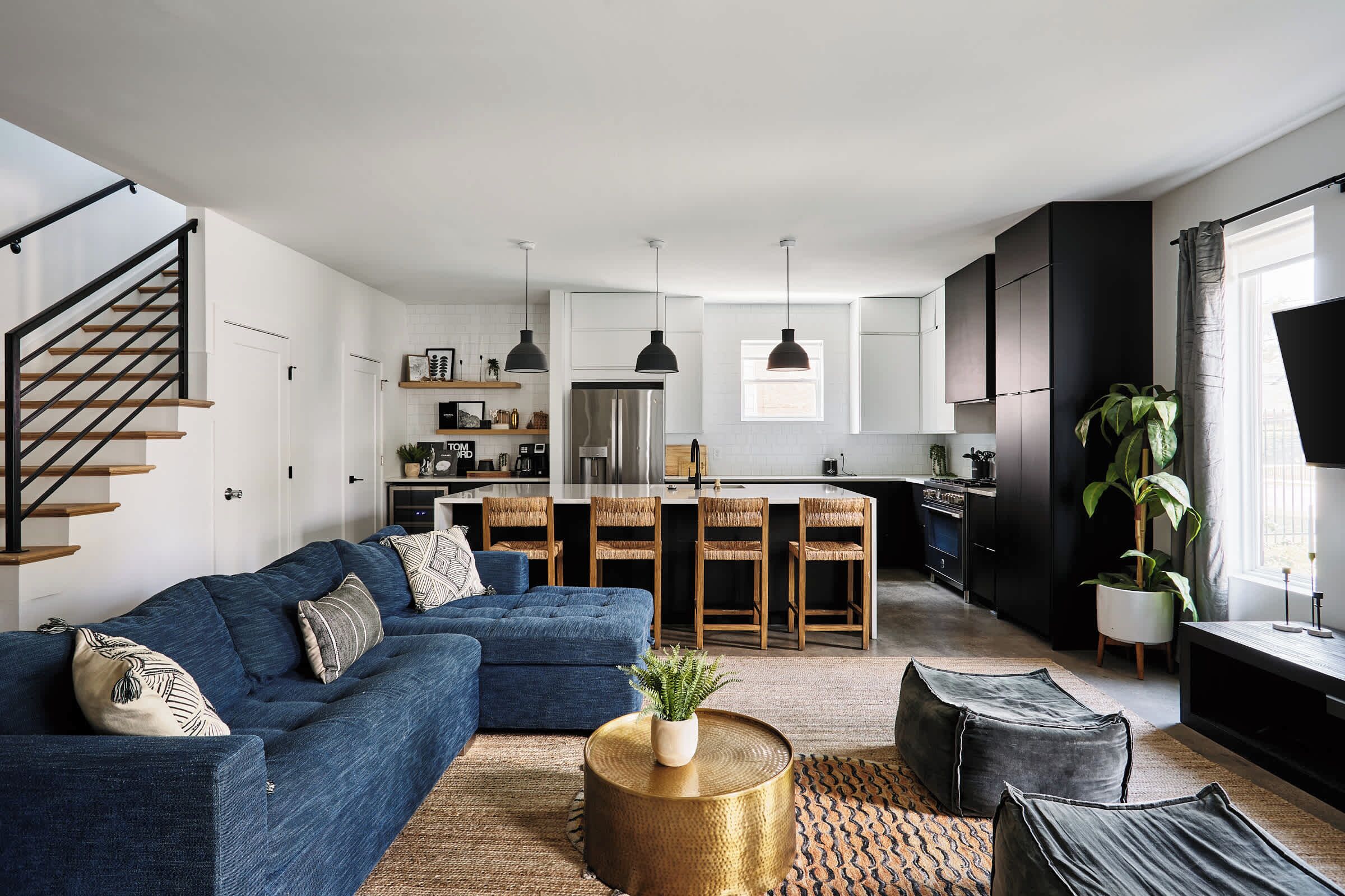 Un salon moderne avec un canapé bleu, une table basse et un escalier.