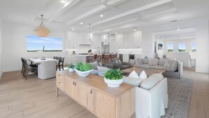 Amplia sala de estar con un sofá grande, una mesa de comedor y una cocina al fondo.