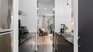 Eine moderne Küche mit Edelstahlgeräten, einem Essbereich aus Holz und Blick zum Wohnbereich.