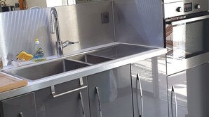 Une cuisine moderne dotée d’un évier en acier inoxydable, d’un four encastré et d’un four à micro-ondes.