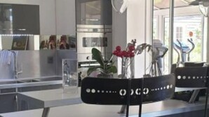 Une cuisine moderne dotée d’un îlot central, d’appareils électroménagers en acier inoxydable et offrant une vue sur l’extérieur.