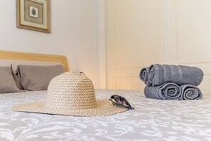 Un lit avec une couvre-lit à motifs, un chapeau de paille et des serviettes enroulées.