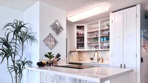 Een moderne keuken met een centraal eiland, witte kasten en een inbouwoven.