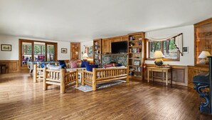 Un salón amplio con suelo de madera, chimenea, televisor y estantería.