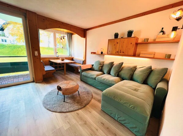 A cozy living room with a green sofa, a wooden table, and a cat tree.